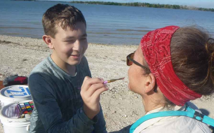 a young person paints on his parents face on an outward bound expedition for families